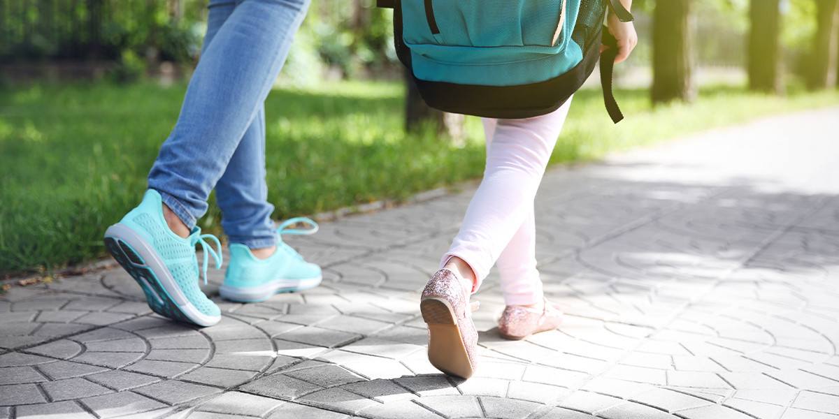 The feet of a child and parent walking to school 